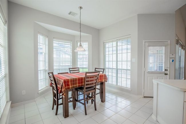 This bright breakfast area features large windows with blinds, offering ample natural light. The space has tiles flooring and neutral walls, creating an inviting and airy atmosphere. | Image 25