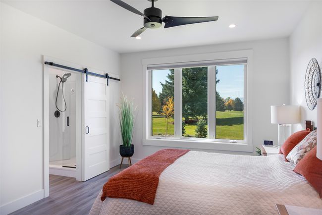 Bedroom with ceiling fan, a barn door, connected bathroom, and wood-type flooring | Image 17