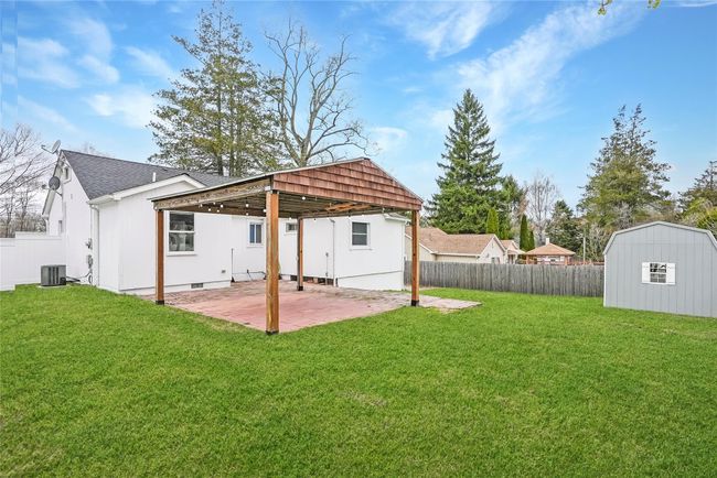 Back of house featuring a patio area, a fenced backyard, an outbuilding, and a yard | Image 23
