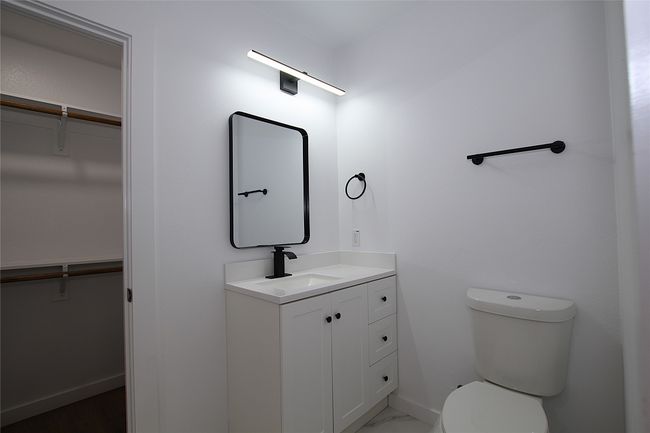 Bathroom with baseboards, a spacious closet, toilet, and vanity | Image 14
