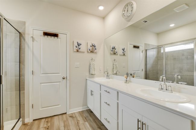 Bathroom featuring a stall shower, wood finished floors, double vanity, and baseboards | Image 21
