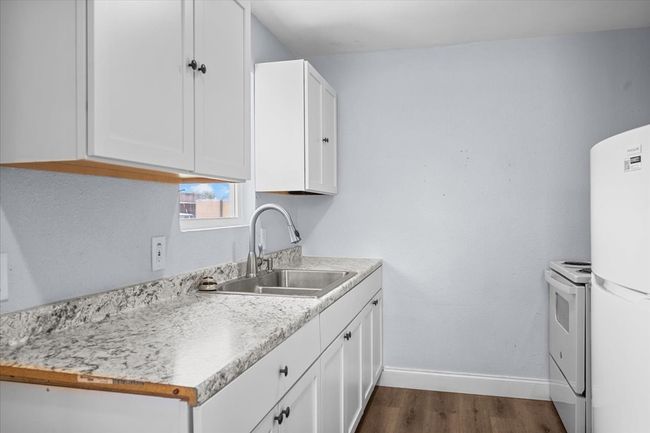 Kitchen featuring a sink, white appliances, white cabinetry, baseboards, and dark wood-style flooring | Image 6
