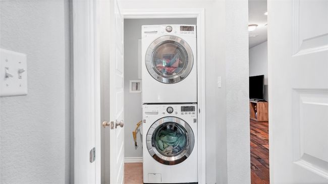 Clothes washing area with stacked washer / drying machine, wood finished floors, and laundry area | Image 9
