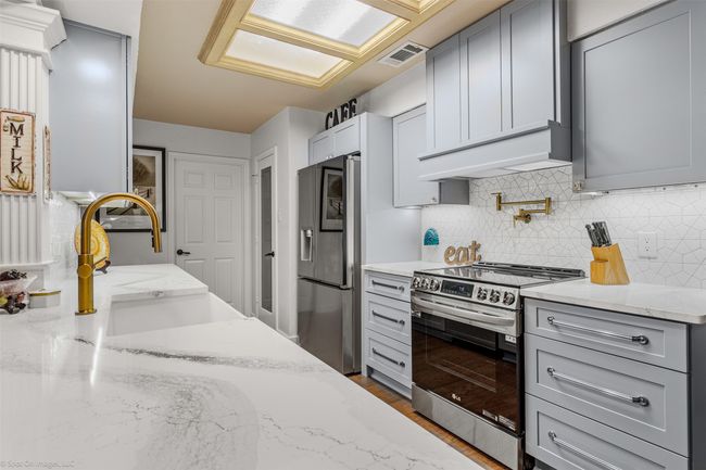 Recently renovated kitchen includes new cabinetry with under cabinet lighting, quartz counters, stainless appliances, breakfast level bar open to living area | Image 4