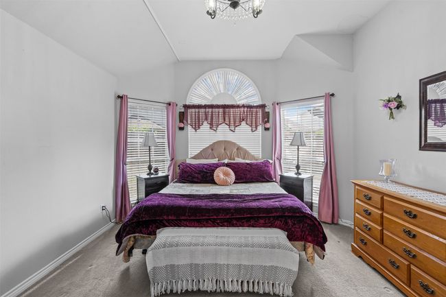 Bedroom with light carpet, vaulted ceiling, baseboards, and a chandelier | Image 13