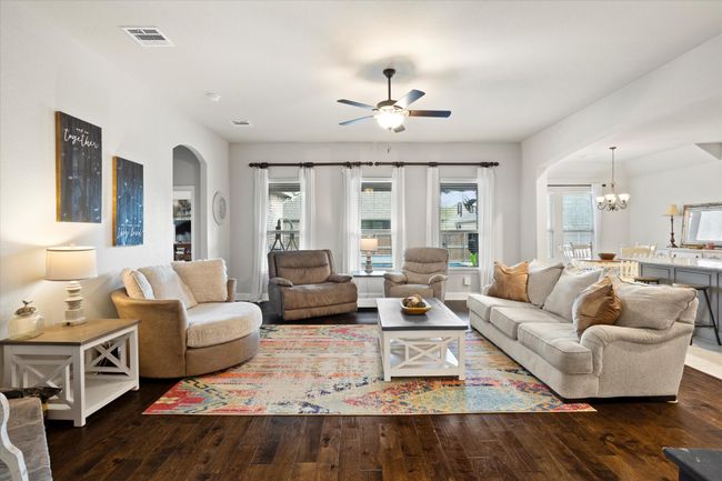 Living area with dark wood-style floors, ceiling fan with notable chandelier, arched walkways, and visible vents | Image 11