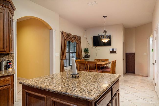 Kitchen with a center island, pendant lighting, light tile patterned floors, light stone counters, and tasteful backsplash | Image 15