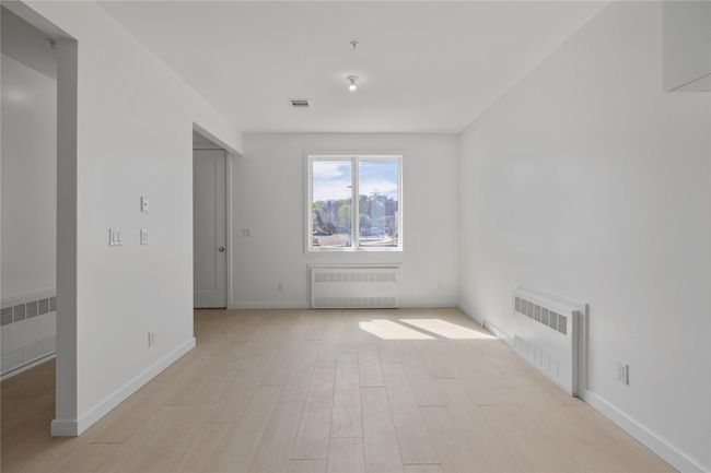 Spare room with baseboards, radiator heating unit, visible vents, and light wood-type flooring | Image 42