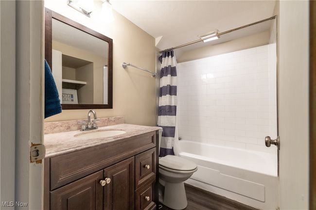Full bathroom featuring wood finished floors, shower / bath combo with shower curtain, toilet, and vanity | Image 11