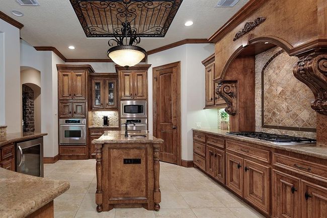 Spacious kitchen features custom cabinetry, center island and modern stainless-steel appliances. Decorative ceiling details add to the elegance of the space. | Image 15