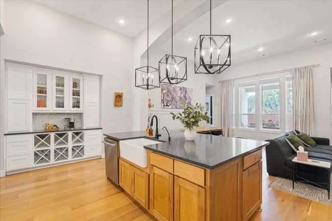 Kitchen with stainless steel dishwasher, a sink, dark countertops, a chandelier, and decorative backsplash | Image 10