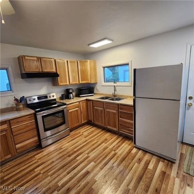 Kitchen with sink, stainless steel appliances, light wood-type flooring, and ceiling fan | Image 3