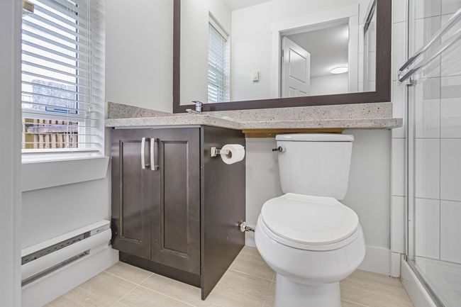 Ensuite Bathroom located below main, featuring tile patterned floors, vanity, and a shower with door | Image 19