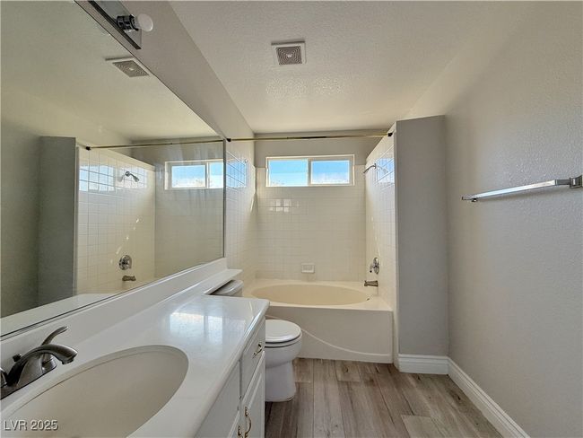 Full bath featuring visible vents, toilet, shower / bathtub combination, wood finished floors, and a textured ceiling | Image 29