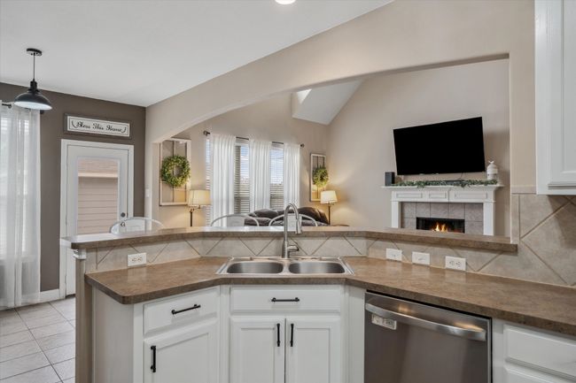 Kitchen with a sink, white cabinetry, open floor plan, decorative backsplash, and dishwasher | Image 9