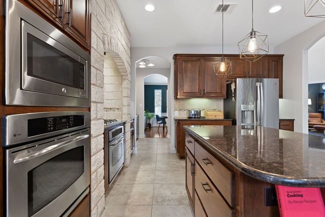 Stainless steel appliances include, two in-wall ovens, gas cooktop, microwave, dishwasher and refrigerator. | Image 13