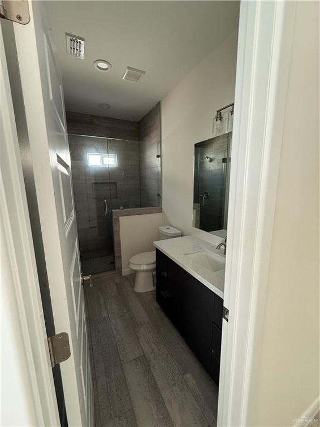 Bathroom featuring wood finished floors, vanity, toilet, a stall shower, and recessed lighting | Image 6
