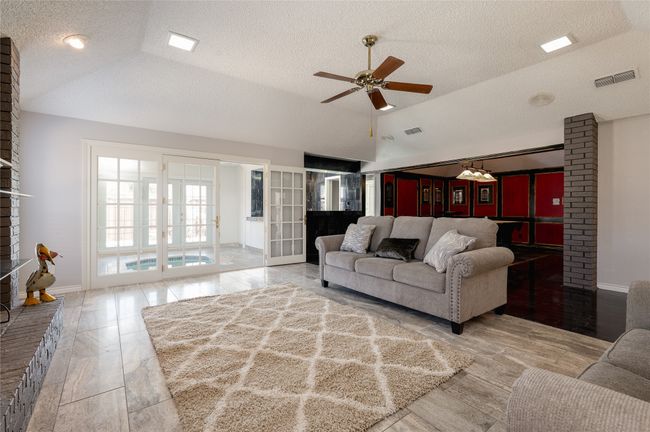 Living room with a ceiling fan, lofted ceiling, visible vents, and a textured ceiling | Image 8