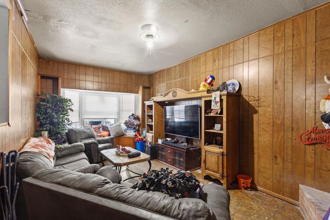 Living room featuring wooden walls and a textured ceiling | Image 5