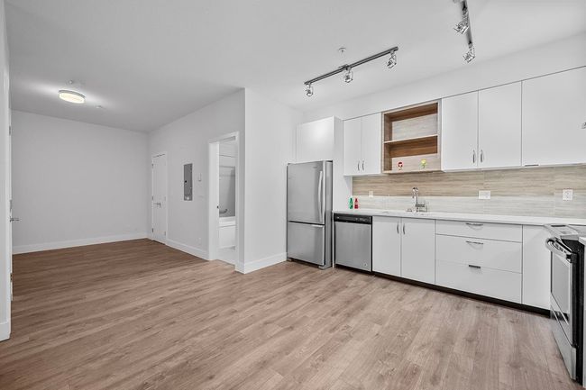 Kitchen with stainless steel appliances, open shelves, light countertops, and light wood-style floors | Image 14