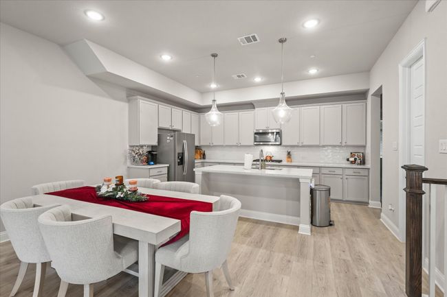 Kitchen featuring stainless steel appliances, light countertops, light wood finished floors, a kitchen island with sink, and recessed lighting | Image 10