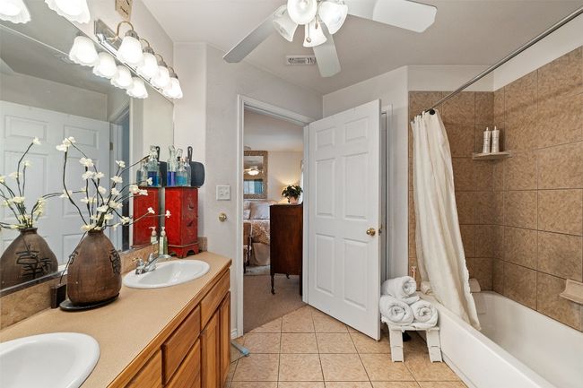 Ensuite bathroom with tile patterned floors, shower / bath combo with shower curtain, double vanity, and a ceiling fan | Image 28