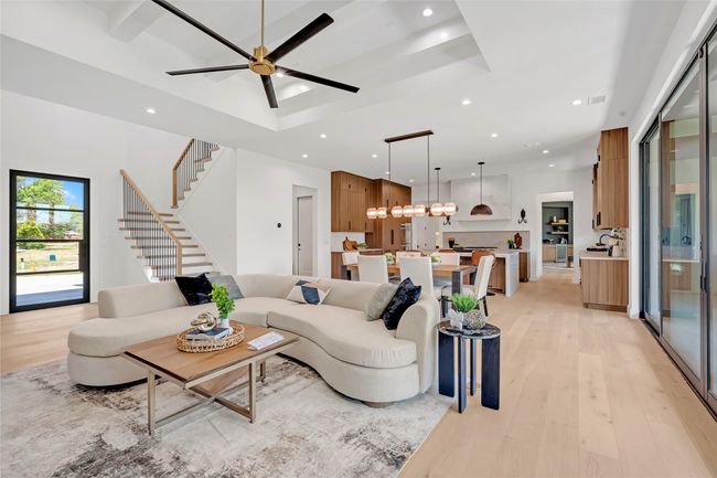 Living room featuring light wood finished floors, recessed lighting, a ceiling fan, stairs, and a chandelier | Image 5