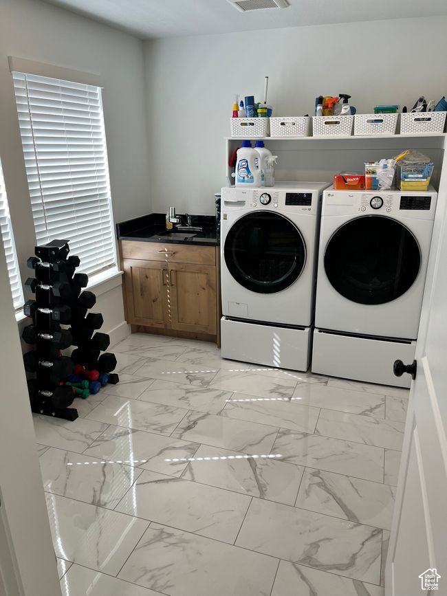 Laundry room with light marble finish floors, washer and clothes dryer, and a sink | Image 21