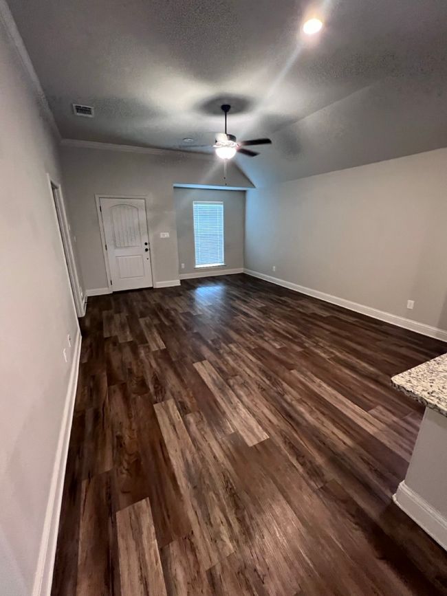 Unfurnished living room featuring dark wood finished floors, baseboards, lofted ceiling, and a textured ceiling | Image 24