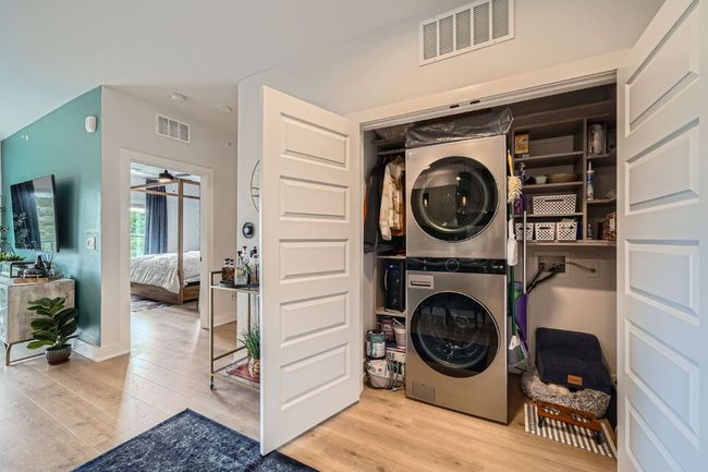 Laundry area featuring stacked washer / dryer, wood finished floors, and ceiling fan | Image 18