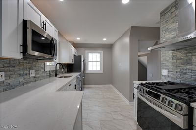 Kitchen featuring appliances with stainless steel finishes, backsplash, white cabinetry, and sink | Image 3