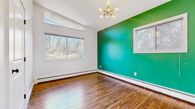 Spare room with a baseboard heating unit, lofted ceiling, an inviting chandelier, and wood finished floors | Image 16