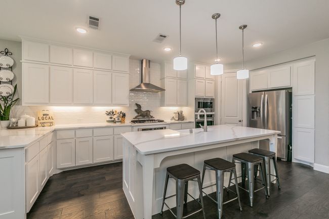 Kitchen featuring dark wood-style floors, appliances with stainless steel finishes, wall chimney range hood, decorative backsplash, and recessed lighting | Image 9