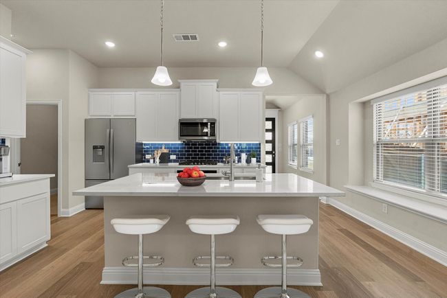 Kitchen featuring appliances with stainless steel finishes, light wood-style flooring, a breakfast bar area, decorative backsplash, and recessed lighting | Image 9
