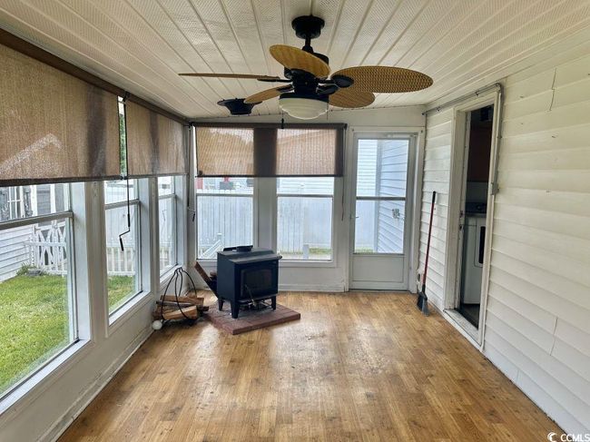 Sunroom featuring a wood stove, a ceiling fan, and plenty of natural light | Image 26