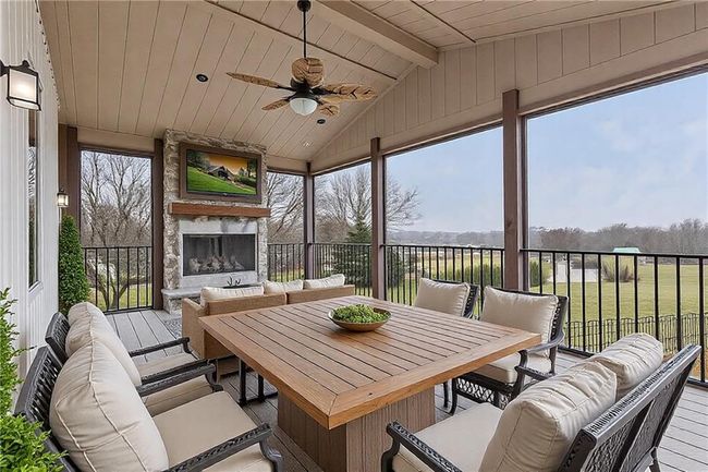 Sunroom featuring lofted ceiling with beams, wooden ceiling, plenty of natural light, and an outdoor stone fireplace | Image 20