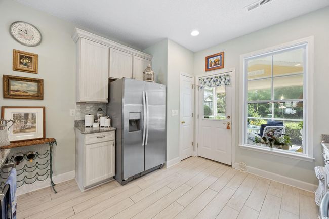 Kitchen featuring stainless steel refrigerator with ice dispenser, decorative backsplash, light wood-type flooring, light stone counters, and recessed lighting | Image 13