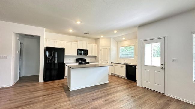 Kitchen with light wood-style floors, white cabinets, black appliances, and a center island | Image 15