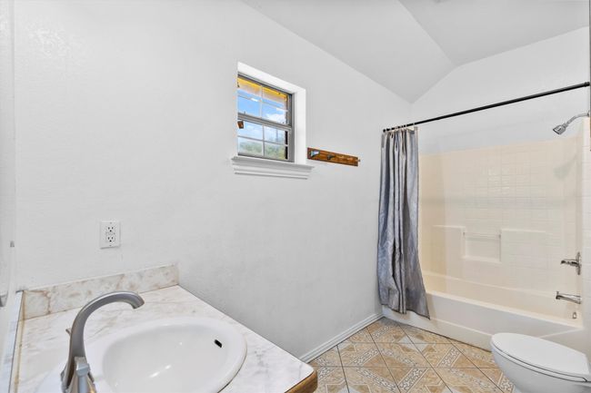 Full bathroom featuring tile patterned flooring, lofted ceiling, toilet, shower / bath combination with curtain, and baseboards | Image 15