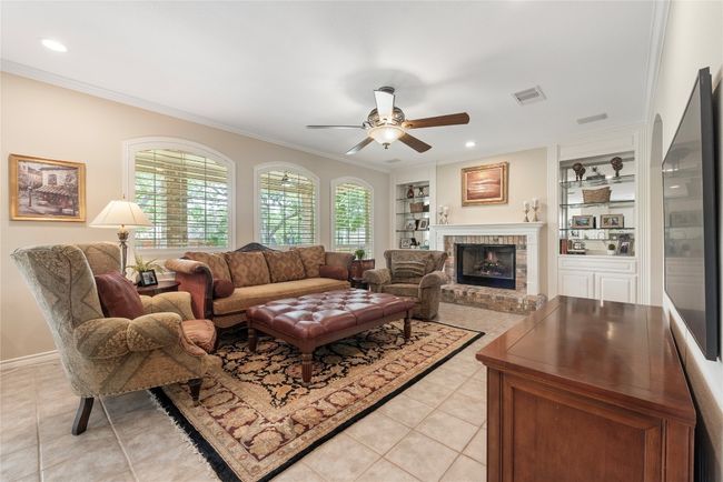 Inviting living room with gas fireplace, built-ins, and a wall of windows overlooking the backyard. | Image 13