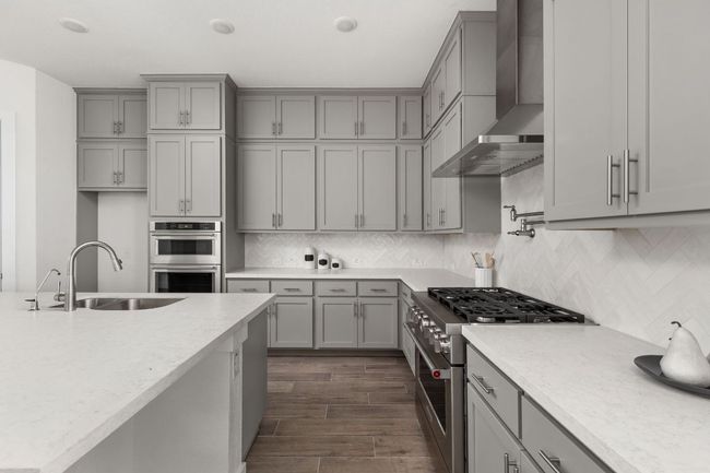 Kitchen with gray cabinets, stainless steel appliances, wall chimney range hood, and a sink | Image 16