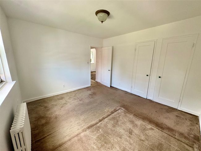 Unfurnished bedroom featuring radiator and carpet | Image 6