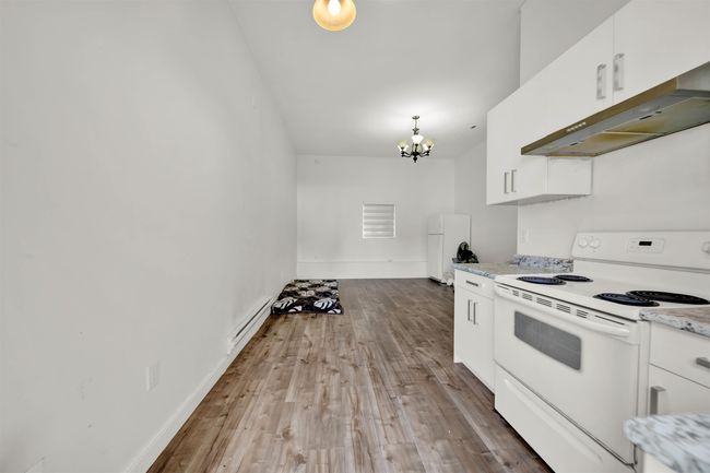 Kitchen featuring white range with electric cooktop, baseboard heating, range hood, and white cabinets | Image 16