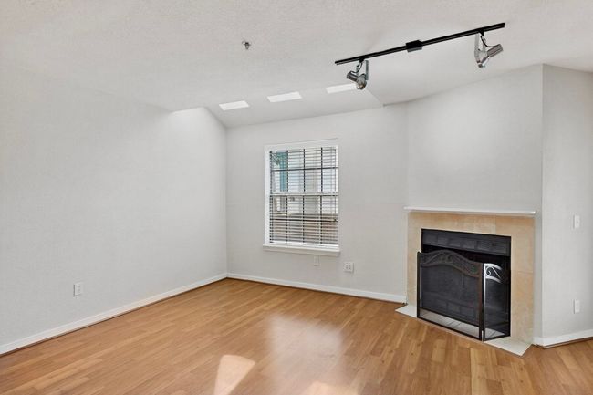 Unfurnished living room featuring a fireplace, track lighting, light wood finished floors, and a textured ceiling | Image 17