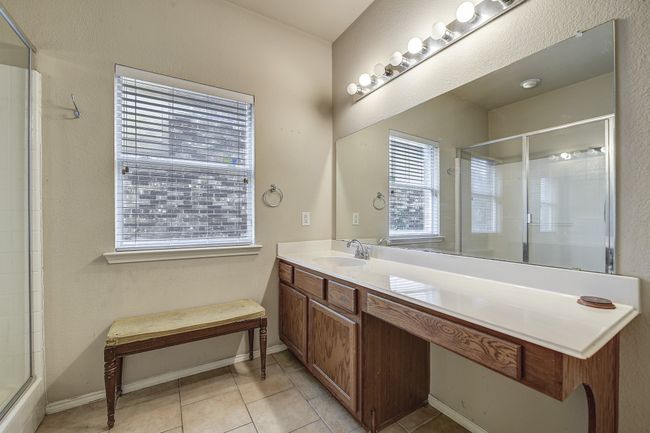 Full bathroom with a stall shower, vanity, light tile patterned flooring, and a textured wall | Image 22