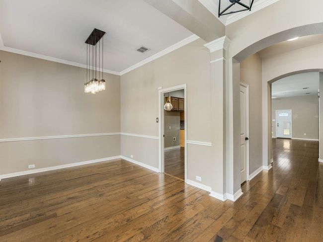 Empty room featuring dark wood-style floors, arched walkways, crown molding, and a chandelier | Image 5