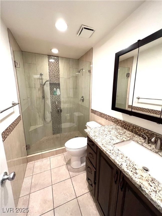 Full bathroom with a shower stall, visible vents, toilet, and tile walls | Image 8