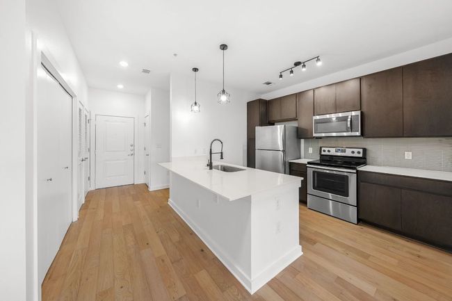 Kitchen with a sink, dark brown cabinetry, light wood-style floors, and stainless steel appliances | Image 4