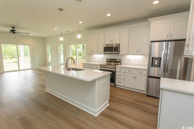 Kitchen with appliances with stainless steel finishes, a sink, a ceiling fan, light wood finished floors, and recessed lighting | Image 4