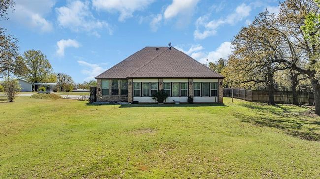 Rear view of house with fence, a lawn, a shingled roof, and brick siding | Image 5